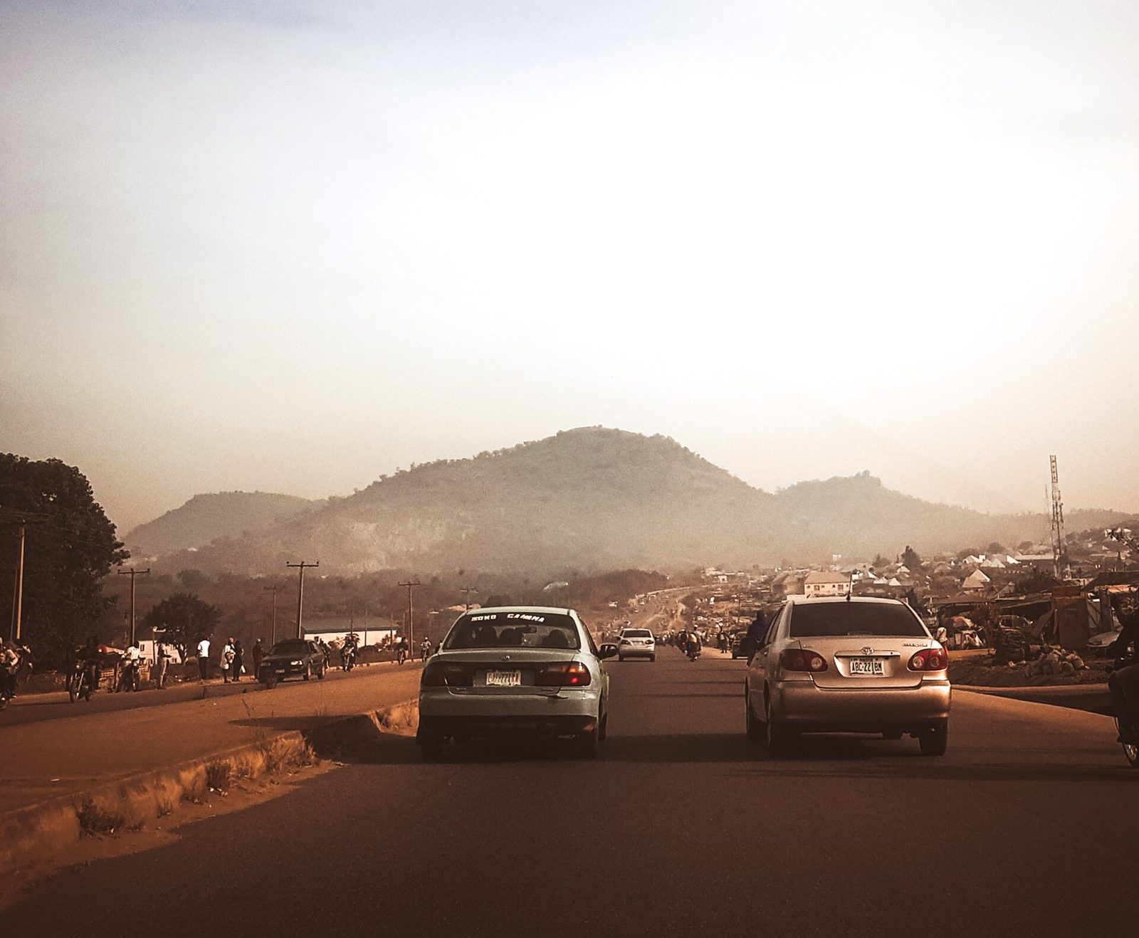 Cars on an Abuja road with hills behind